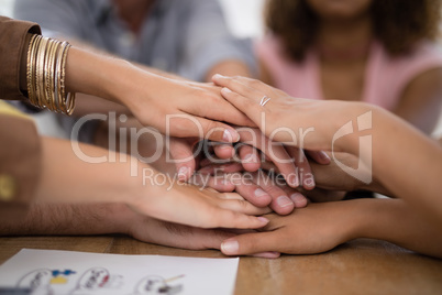 Executives forming hand stack on table