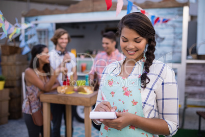 Happy waitress writing order in notepad