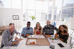 Portrait of executives having pizza in conference room