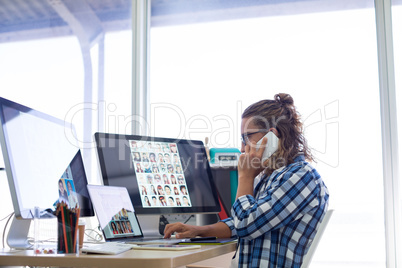 Male executive talking on mobile phone while working at his desk