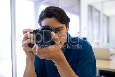 Male executive clicking a picture on digital camera