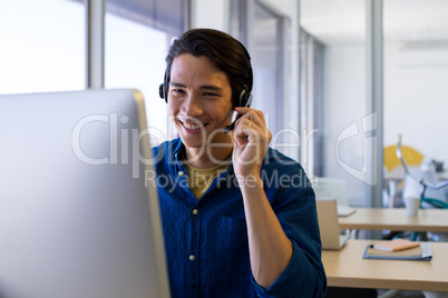 Male executive in headset working over computer at his desk Male executive in headset working over computer at his desk