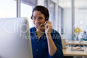 Male executive in headset working over computer at his desk