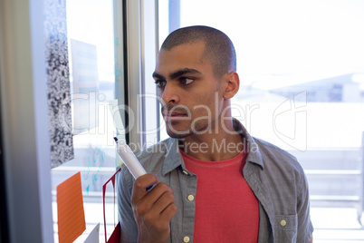 Male executive reading sticky notes on glass door