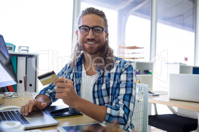 Male executive doing online shopping on laptop at his desk