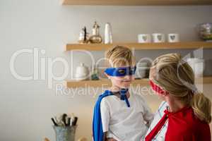 Mother and son pretending to be superhero in the kitchen