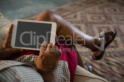 Senior man using digital tablet in the living room at home