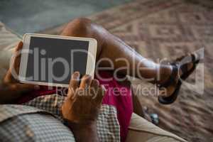 Senior man using digital tablet in the living room at home