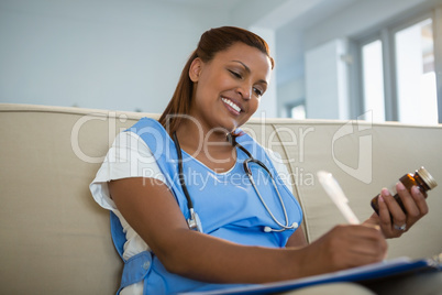 Doctor holding pills bottle and writing prescription
