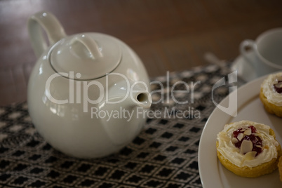Teapot and dessert on place mat