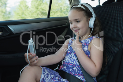 Cute girl using mobile phone while listening music