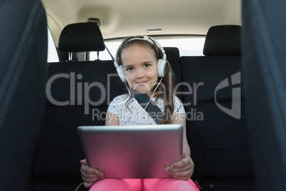 Portrait of cute girl listening music on headphone from digital tablet