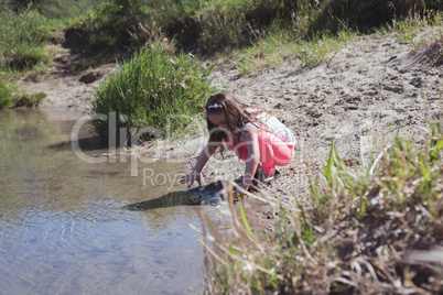 Little girl playing at riverbank