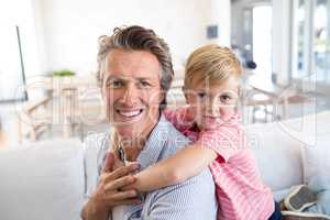 Happy father and son relaxing on sofa in living room