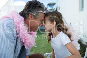 Smiling father and daughter in fairy costume standing face to face