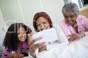 Family taking selfie on mobile phone in bedroom