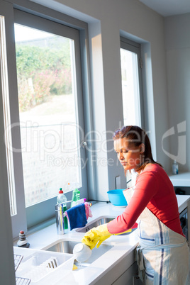 Woman washing utensil in kitchen sink