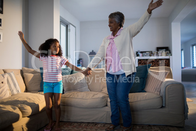 Grandmother and granddaughter dancing in living room