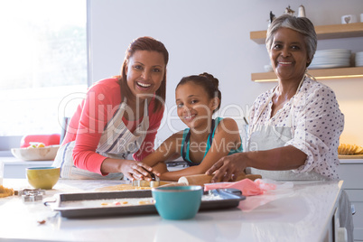 Happy multi-generation family preparing gingerbread in kitchen