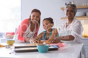 Happy multi-generation family preparing gingerbread in kitchen