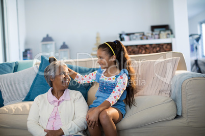 Granddaughter brushing her grandmothers hair in living room