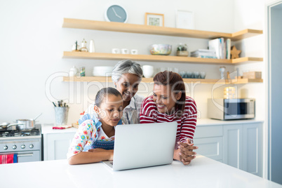 Happy family using laptop in kitchen worktop