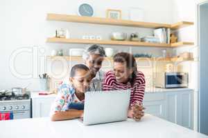 Happy family using laptop in kitchen worktop