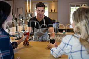 Bartender serving drinks to young friends