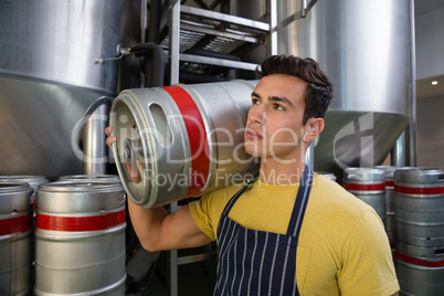 Worker looking away while carrying keg