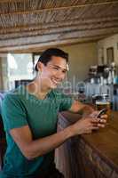 Smiling man looking away while using phone at bar