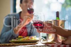 Cropped hand of woman with friend holding wineglass