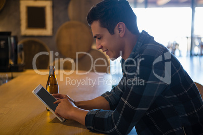 Side view of man using tablet at bar