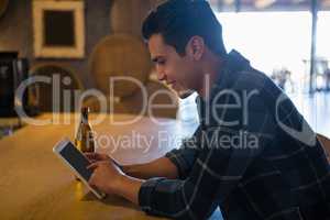 Side view of man using tablet at bar