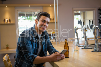 Portrait of man using phone at bar