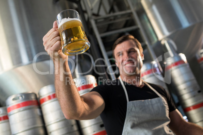 Low angle view of smiling worker holding beer glass