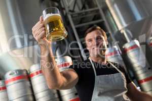 Low angle view of smiling worker holding beer glass