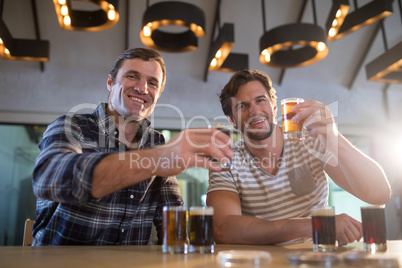 Portrait of happy friends holding beer glass