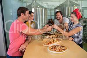 Happy friends toasting beer at table in restaurant