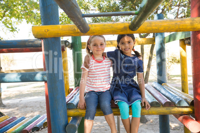 Portrait of smiling girls with arms around sitting on jungle gym