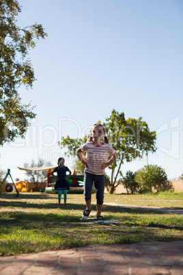 Girls with hands on hip jumping on grassy field