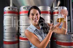 Portrait of smiling worker examining beer in beaker at factory