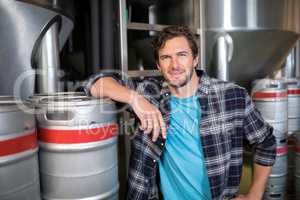 Confident worker standing by kegs at warehouse