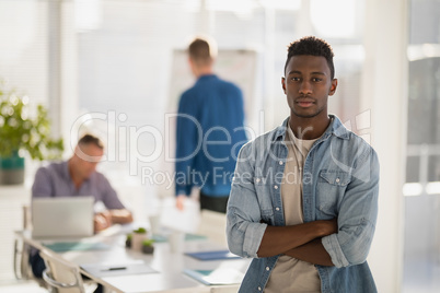 Male executive standing with arms crossed in the office