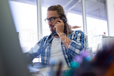 Male executive talking on phone while working at his desk
