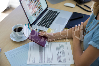 Female executive holding tickets and passport at her desk