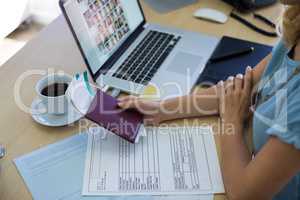 Female executive holding tickets and passport at her desk