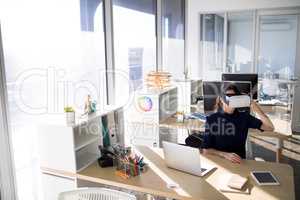 Female executive using virtual reality headset at her desk