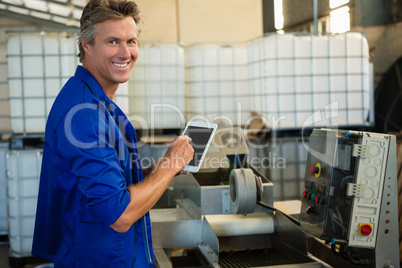 Smiling worker using digital tablet in factory