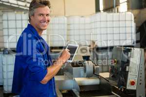Smiling worker using digital tablet in factory