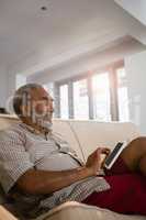 Senior man using digital tablet in the living room